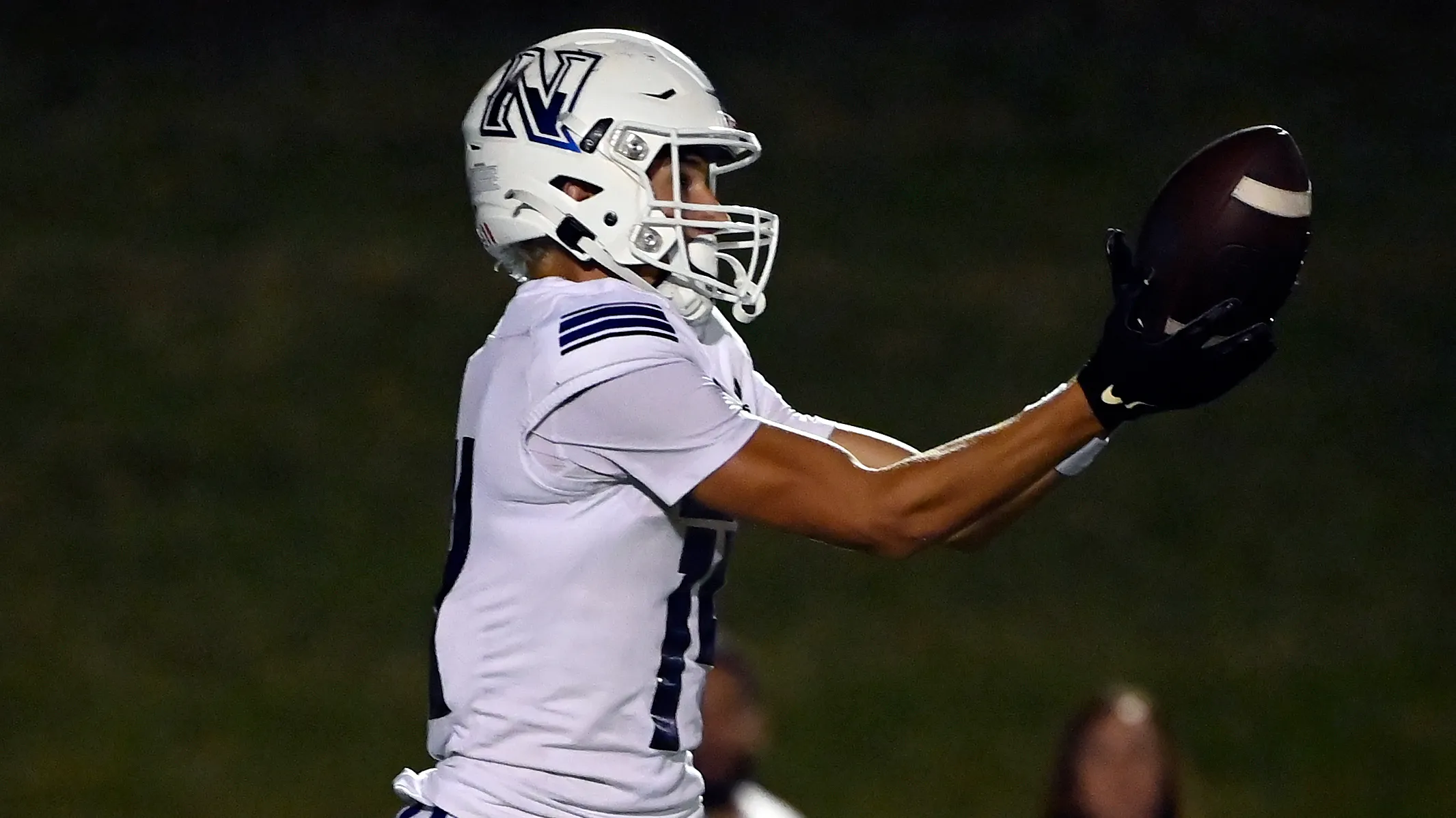 Student athlete celebrating a touchdown, holding the football overhead